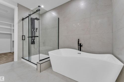 Modern bathroom featuring a freestanding soaking tub and a glass-enclosed shower with a multi-function shower panel - 2611 62 Avenue, Rural Leduc County, AB - Indoor Photo Showing Bathroom