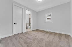 Carpeted interior space featuring light grey walls, white trim, a single window with white framing, and a flush-mount ceiling light - 