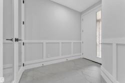 Entryway featuring wainscoting, large format tile flooring, and a glass-paneled door with matte black hardware - 