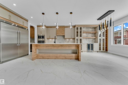 Gourmet kitchen featuring a large wood-finish island, integrated stainless steel appliances, stone countertops, and extensive custom cabinetry - 2611 62 Avenue, Rural Leduc County, AB - Indoor Photo Showing Kitchen