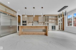 Gourmet kitchen featuring a large wood-finish island, integrated stainless steel appliances, stone countertops, and extensive custom cabinetry - 