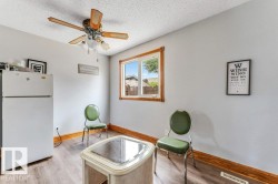 Room featuring light gray walls, wood-finish flooring, a window with wood trim, and a ceiling fan with light fixture - 