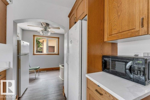 Kitchen area featuring wood-finish cabinetry, white countertops, and a window with wood trim - 14530 37 Street, Edmonton, AB 