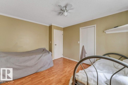 Room featuring wood-finish flooring, neutral wall tones, and white crown molding - 14530 37 Street, Edmonton, AB 