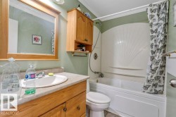 Bathroom featuring a built-in tub/shower combination, a vanity with a drop-in sink, and wood cabinetry - 