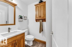 Bathroom vanity featuring a light-colored countertop with an integrated sink, wood-finish cabinetry, and a framed mirror - 