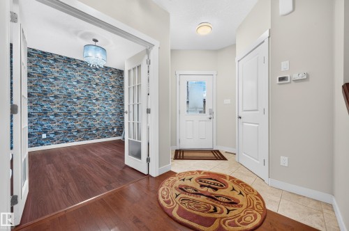 Entry foyer featuring tile flooring, a white paneled entry door with frosted glass, and white trim - 1512 Cunningham Cape, Edmonton, AB 