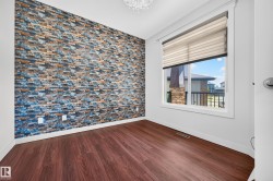 Feature wall with stacked stone-look finish, wood-finish flooring, white baseboards, window with blinds, and ceiling-mounted light fixture - 