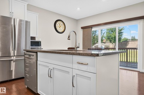 Kitchen island featuring an undermount sink, gooseneck faucet, and stone countertop - 1512 Cunningham Cape, Edmonton, AB 