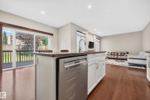 Kitchen island with a stone-finish countertop, undermount sink, and stainless steel dishwasher - 1512 Cunningham Cape, Edmonton, AB 