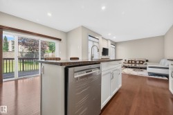 Kitchen island with a stone-finish countertop, undermount sink, and stainless steel dishwasher - 