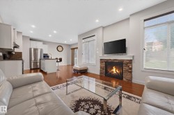 Living area featuring a stone-clad fireplace with a white mantel, recessed lighting, and rich wood-finish flooring - 