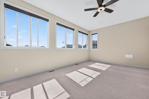 Spacious room featuring multiple large windows with roller shades, neutral-toned walls, and plush carpeting - 1512 Cunningham Cape, Edmonton, AB 