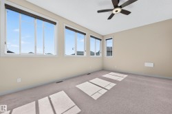 Spacious room featuring multiple large windows with roller shades, neutral-toned walls, and plush carpeting - 