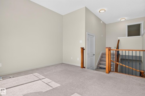 Upper-level landing featuring neutral carpet, light-toned walls, and a staircase with wood newel posts and metal spindles - 1512 Cunningham Cape, Edmonton, AB 