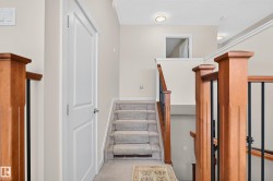 Carpeted staircase featuring wood-finish newel posts and black wrought iron spindles - 