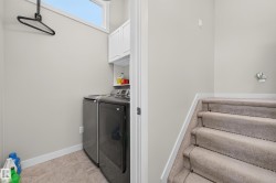 Dedicated laundry area featuring a front-loading washer and dryer, upper cabinetry, and tile flooring - 