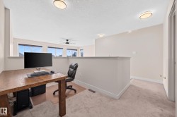 Open loft area featuring neutral carpeting, a partial wall, and multiple windows - 