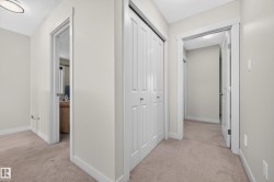 Hallway featuring light neutral wall paint, white trim, beige carpeting, a bi-fold closet, and recessed lighting - 