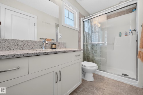Bathroom vanity featuring a speckled countertop, undermount sink, and chrome faucet - 1512 Cunningham Cape, Edmonton, AB 