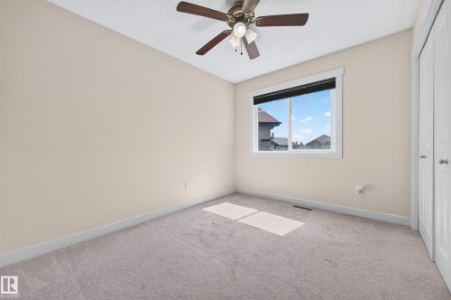 Neutral-toned room featuring a single window, a ceiling fan with integrated lighting, and light-colored carpeting - 1512 Cunningham Cape, Edmonton, AB 