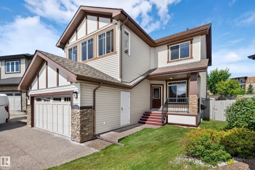 Two-story residence featuring light-toned siding and stone veneer accents - 1512 Cunningham Cape, Edmonton, AB 