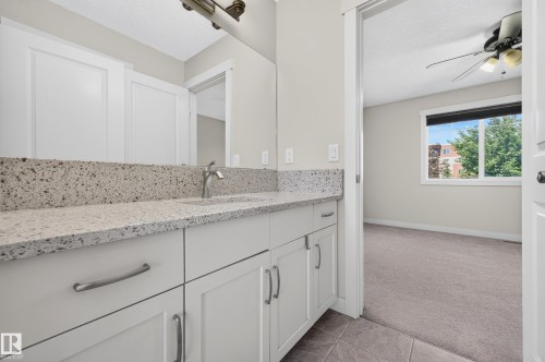 Bathroom vanity featuring a speckled countertop, integrated sink, and brushed nickel faucet - 1512 Cunningham Cape, Edmonton, AB 