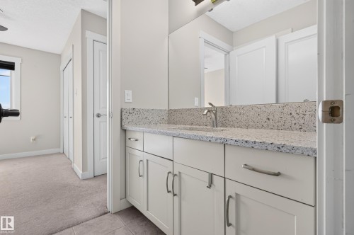 Bathroom vanity with a speckled countertop, undermount sink, and brushed nickel faucet - 1512 Cunningham Cape, Edmonton, AB 
