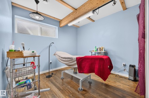 Room featuring wood-finish flooring, exposed wood beams, and a high horizontal window - 1512 Cunningham Cape, Edmonton, AB 