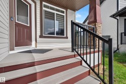 Covered front porch featuring durable composite decking, contrasting dark brown trim, and a robust black metal railing - 