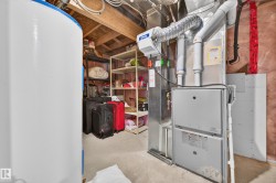 Utility area featuring a water heater, furnace, exposed wood joists, and concrete flooring - 