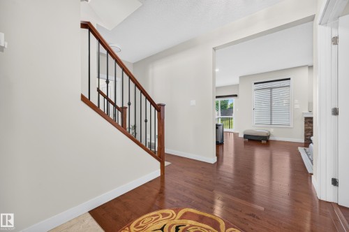 Foyer featuring hardwood flooring and a staircase with wood handrails and black metal spindles - 1512 Cunningham Cape, Edmonton, AB 