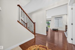 Foyer featuring hardwood flooring and a staircase with wood handrails and black metal spindles - 