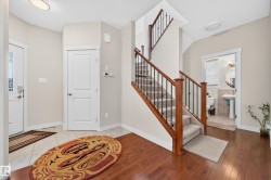 Inviting entryway featuring wood-finish flooring, a carpeted staircase with wood and metal railings, and a tiled landing - 