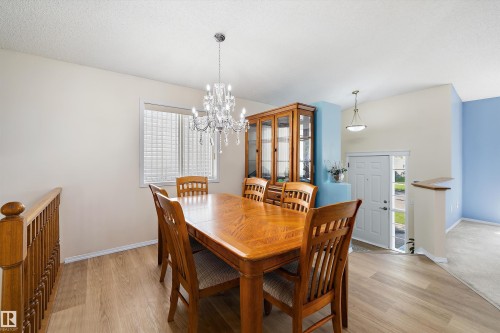Dining area featuring wood-finish flooring, a crystal chandelier, and a window with blinds - 15016 134 Street, Edmonton, AB 