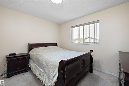 Carpeted bedroom featuring light-toned walls and a window with vertical blinds - 15016 134 Street, Edmonton, AB 