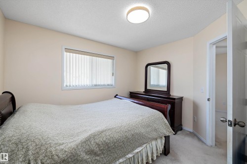 Bedroom featuring neutral wall color, carpet flooring, a window with vertical blinds, and a flush mount ceiling light fixture - 15016 134 Street, Edmonton, AB 