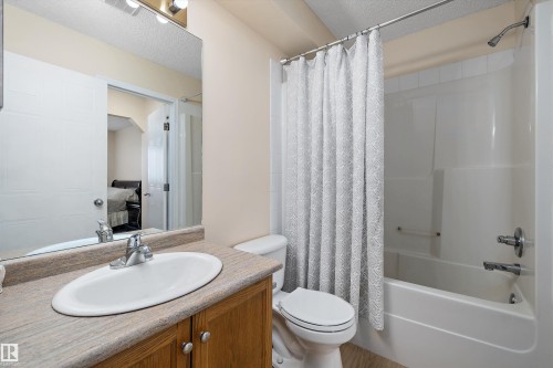 Full bathroom featuring a single vanity with wood cabinetry, a rectangular basin, and a light-toned countertop - 15016 134 Street, Edmonton, AB 