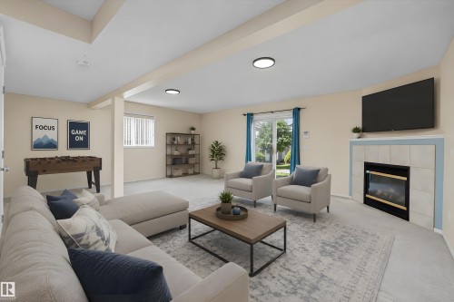 Spacious living area featuring carpet flooring, recessed lighting, and a fireplace with a tiled surround - 15016 134 Street, Edmonton, AB 