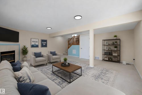 Spacious lower-level area featuring recessed lighting, a fireplace with a light-colored tile surround, and a visible staircase with wooden railings - 15016 134 Street, Edmonton, AB 