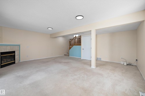 Spacious finished room featuring carpet flooring, recessed lighting, and a tiled fireplace - 15016 134 Street, Edmonton, AB 