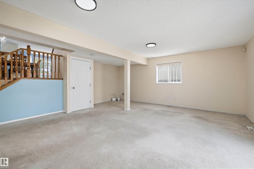 Expansive carpeted room featuring a drop ceiling, recessed lighting, and a window with blinds - 15016 134 Street, Edmonton, AB 
