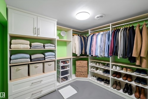 Custom closet organization system featuring white cabinetry, light wood-finish shelving, and integrated hanging rods - 15016 134 Street, Edmonton, AB 