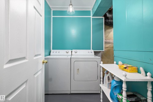 Dedicated laundry area featuring a washer and dryer, vibrant wall panels with white trim, a built-in shelf, and overhead lighting - 15016 134 Street, Edmonton, AB 