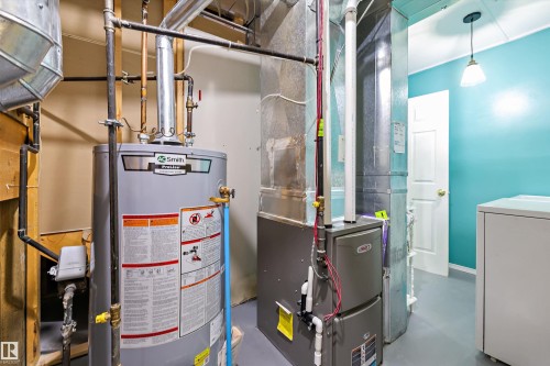 Utility area featuring a water heater, furnace, and exposed ductwork - 15016 134 Street, Edmonton, AB 