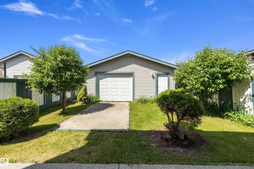 Detached garage with horizontal siding, a paneled overhead door, and a side entry door - 15016 134 Street, Edmonton, AB 