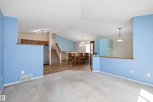 Carpeted living area with light blue walls and a vaulted ceiling - 15016 134 Street, Edmonton, AB 