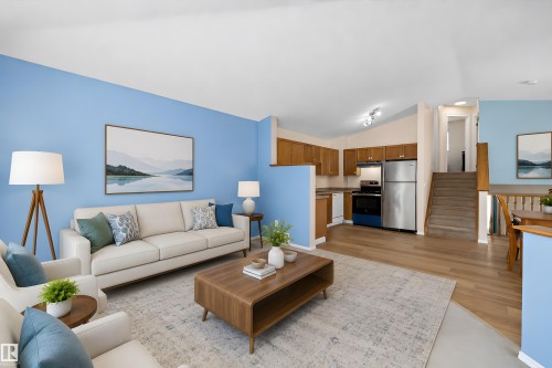 Open-concept living space featuring wood-finish flooring, a kitchen with wood cabinetry and stainless steel appliances, and a staircase with wood railings - 15016 134 Street, Edmonton, AB 