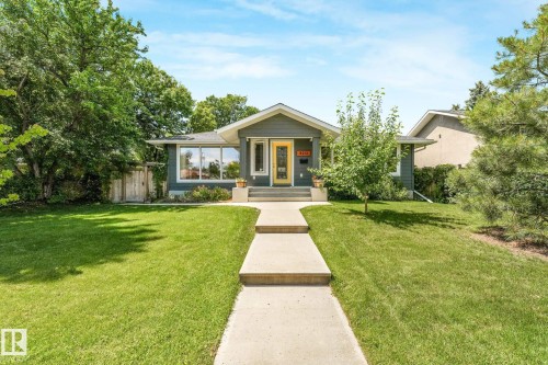 Contemporary bungalow with a gray exterior, a vibrant yellow front door, and a concrete walkway - 8212 148 Street Nw, Edmonton, AB 