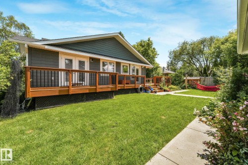 Expansive rear yard featuring a manicured lawn, concrete pathway, and mature landscaping - 8212 148 Street Nw, Edmonton, AB 